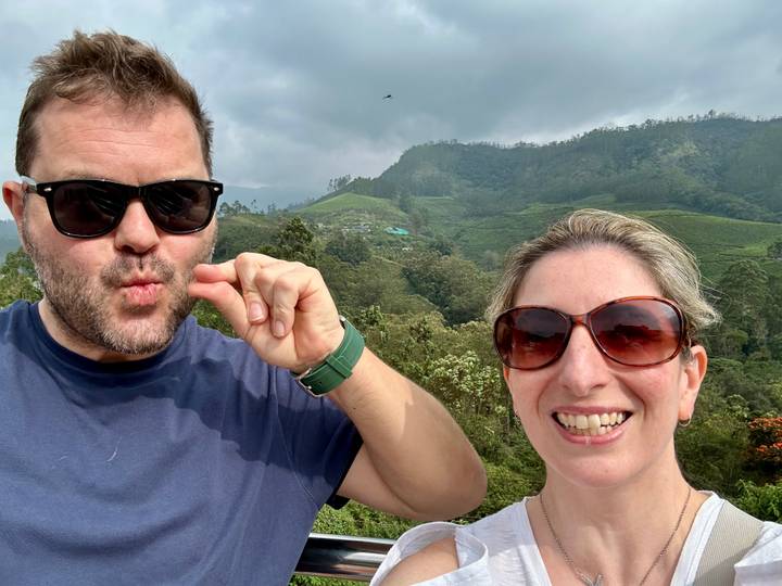 A couple taking a selfie with tea plantations in the background.