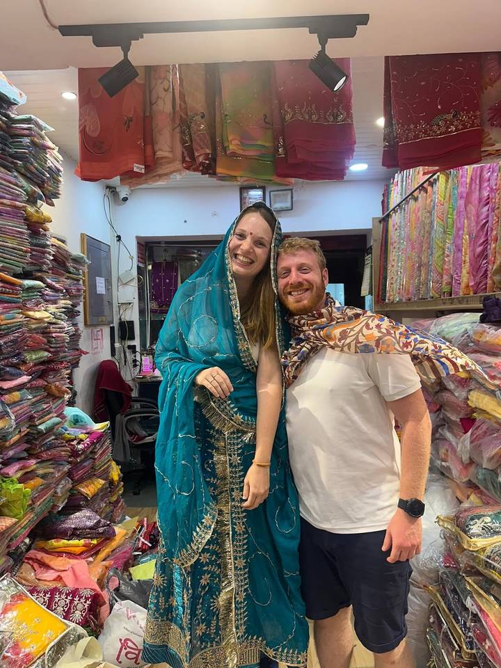 Couple trying on traditional Indian clothing in a shop.