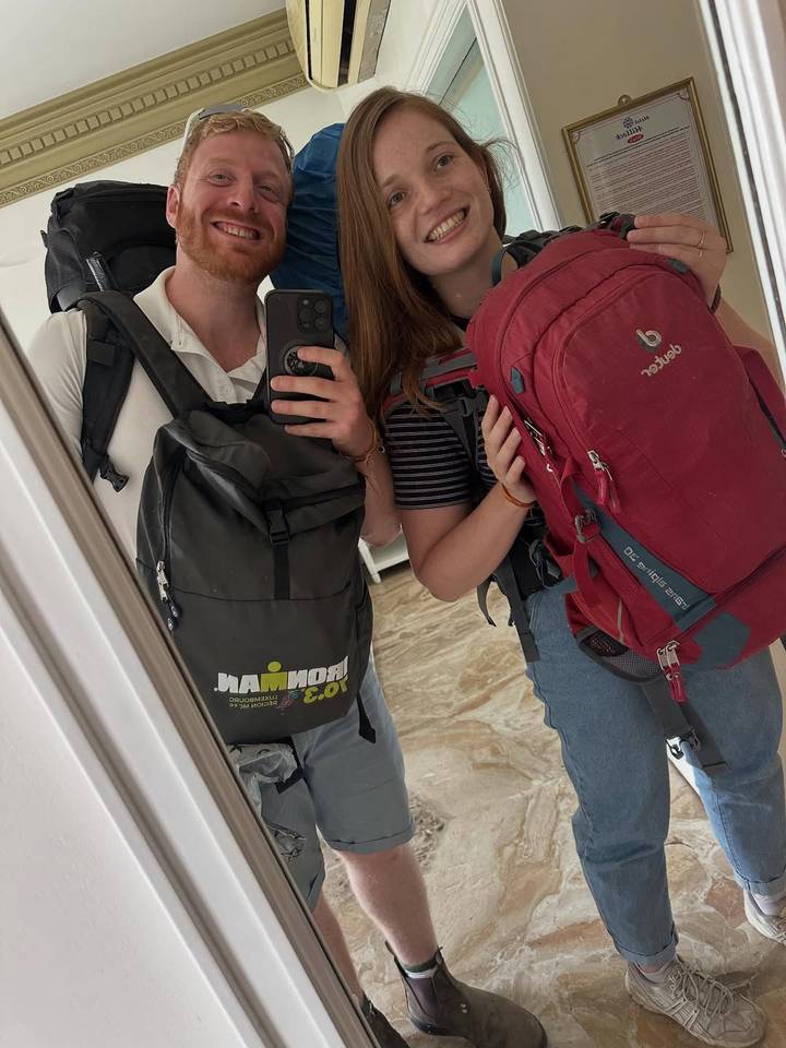 Two people with backpacks and reflection in a mirror.