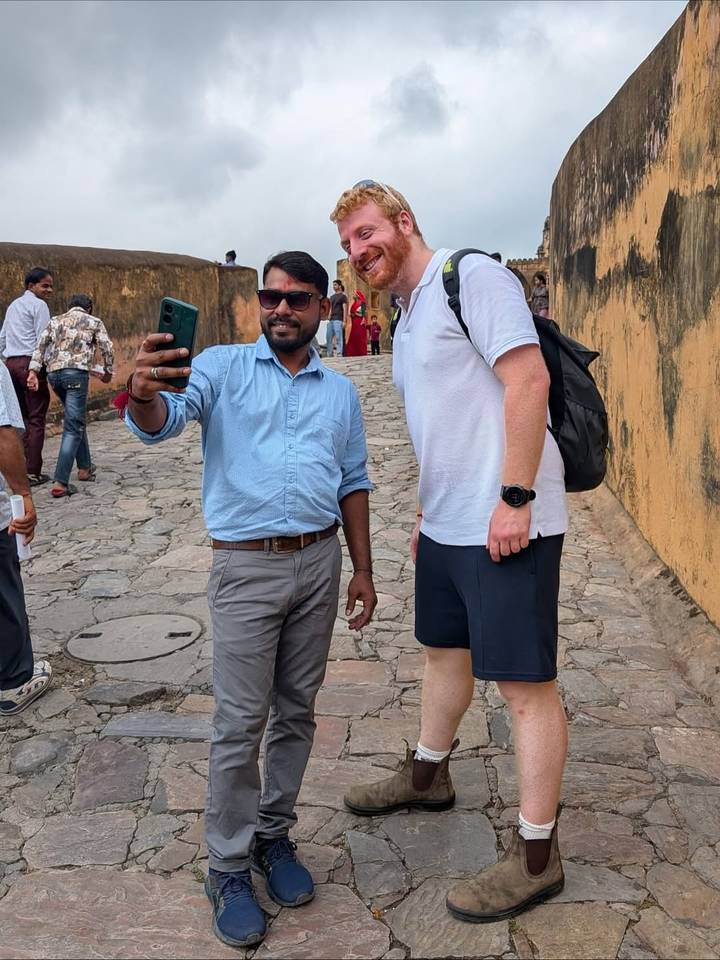 Two men taking a selfie on a cobblestone street.