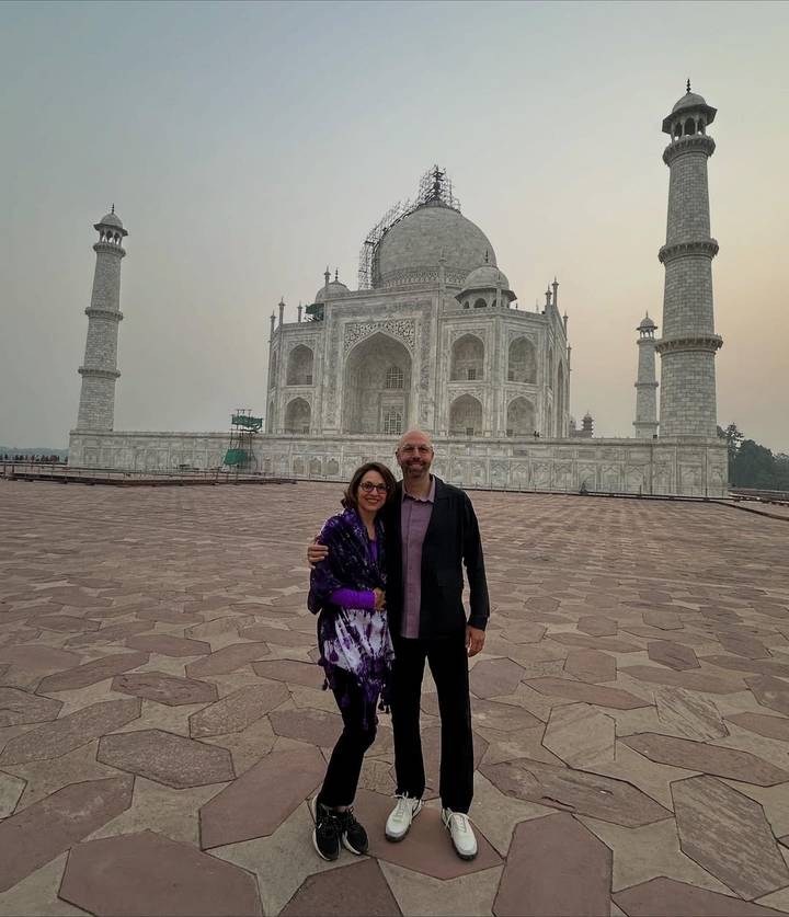 Couple posing in front of the Taj Mahal at sunrise.