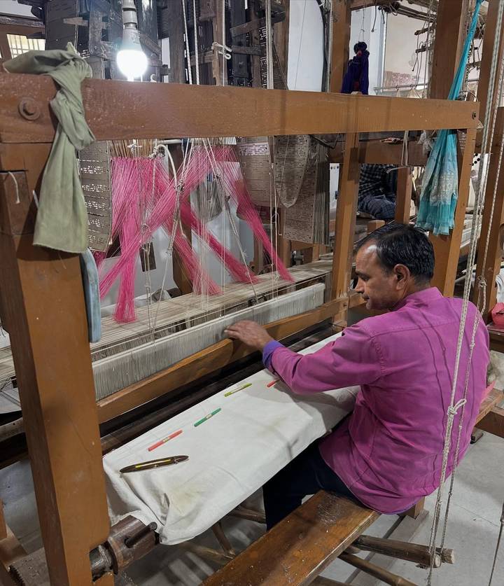 Man weaving on a loom in a textile workshop.