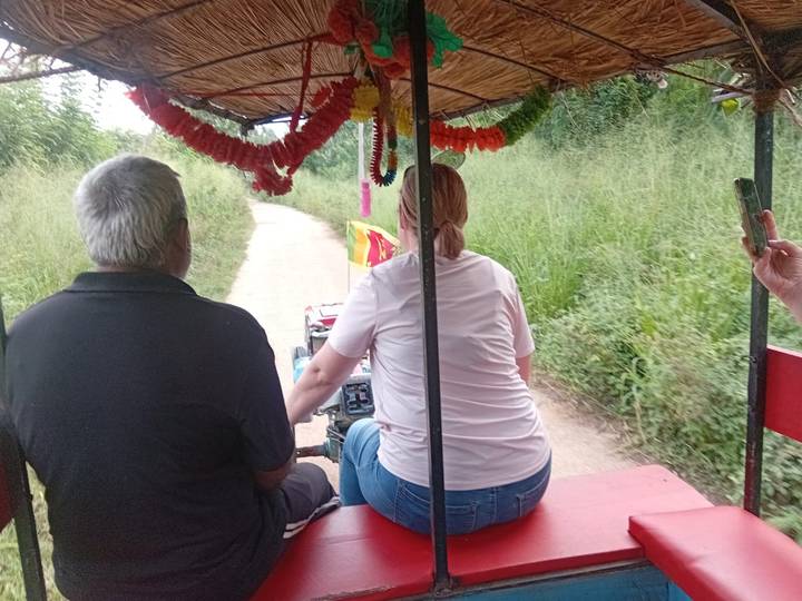 Vista trasera de dos personas montando un vehículo pequeño por un sendero.