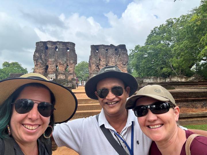 Tres personas con sombreros posando frente a ruinas antiguas.