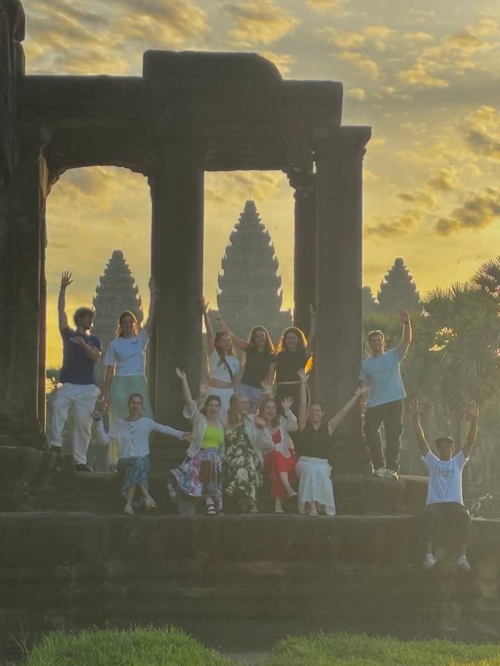 Een groep mensen die poseert voor Angkor Wat bij zonsopgang.