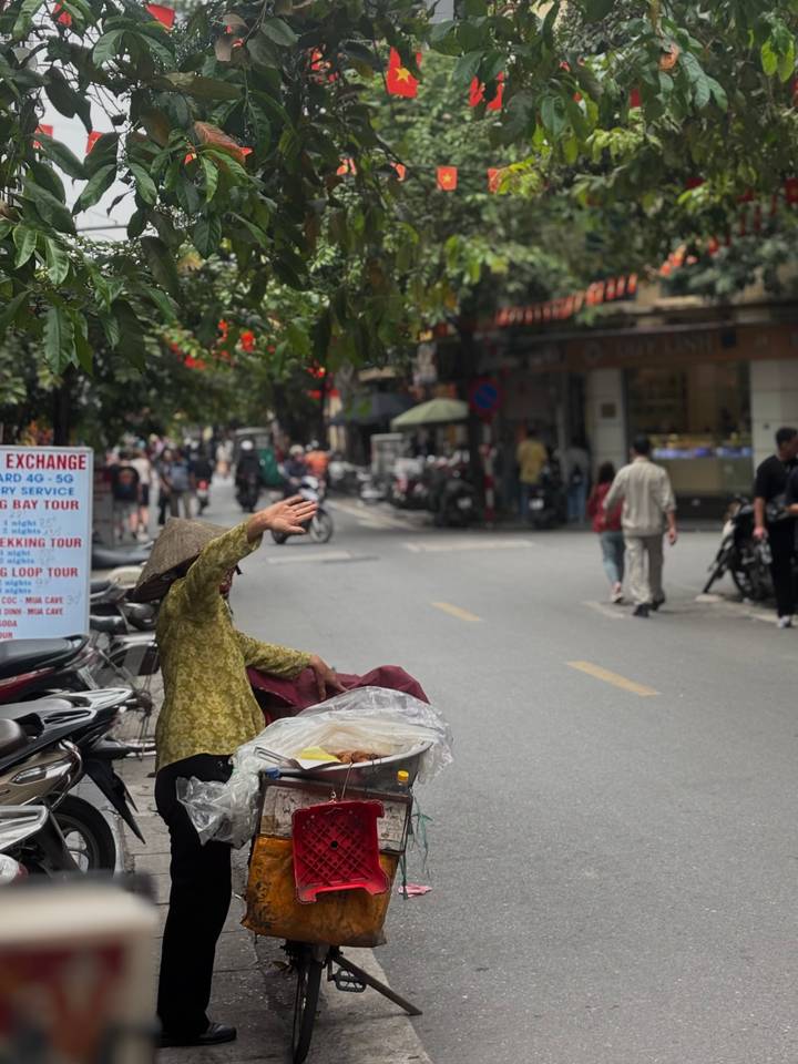 Een persoon op een drukke straat die zwaait met een kegelvormige hoed.