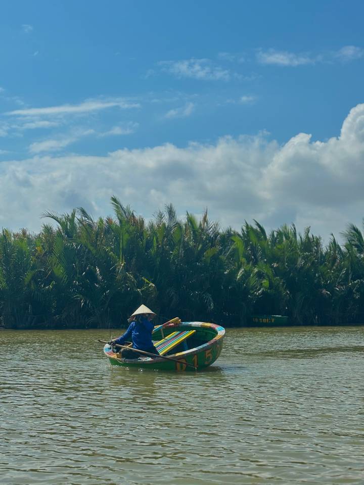 Een persoon in een kleurrijke boot die op een rivier roeit.