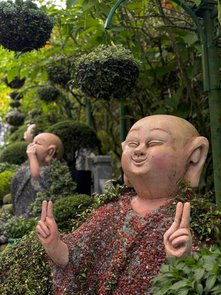 Beelden van glimlachende monniken in een tuin.