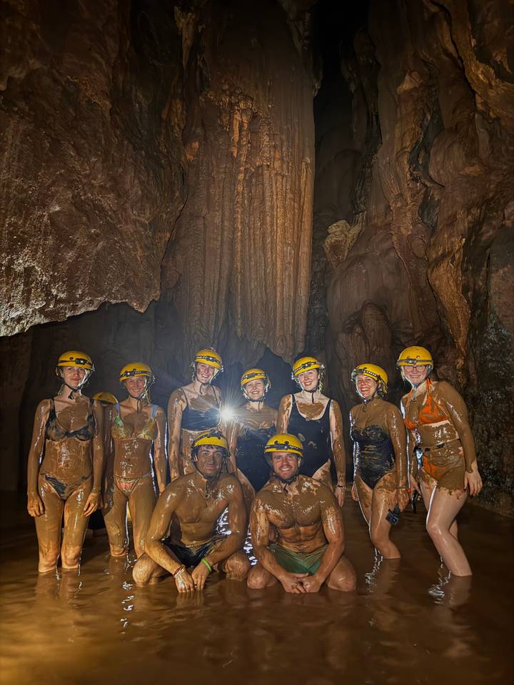 Groep die een modderige grot verkent met helmen op.