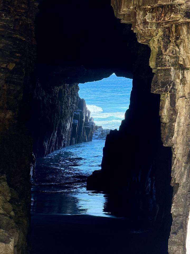 Vista a través de la abertura de una cueva hacia un océano azul.