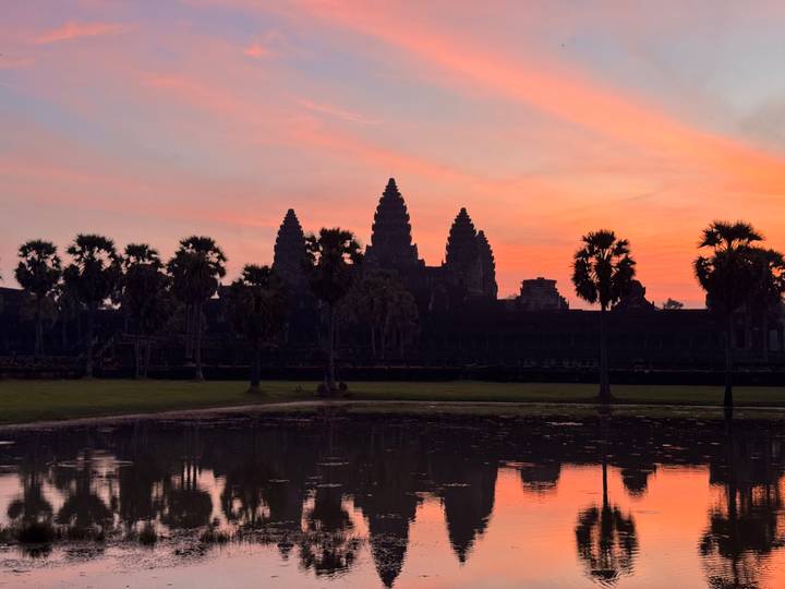 Angkor Wat tijdens zonsondergang met warme tinten die weerkaatsen in het water.