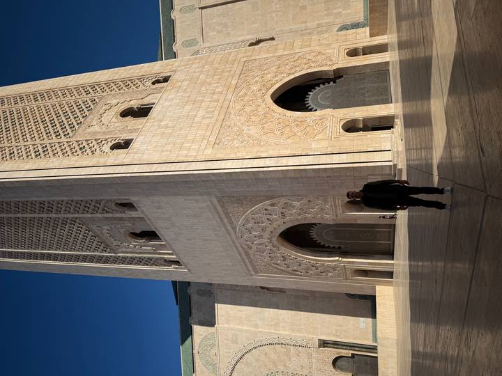 Een persoon die voor een grote historische toren staat.