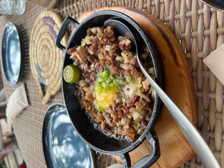 Nahaufnahme eines brutzelnden Gerichts, das serviert wird.