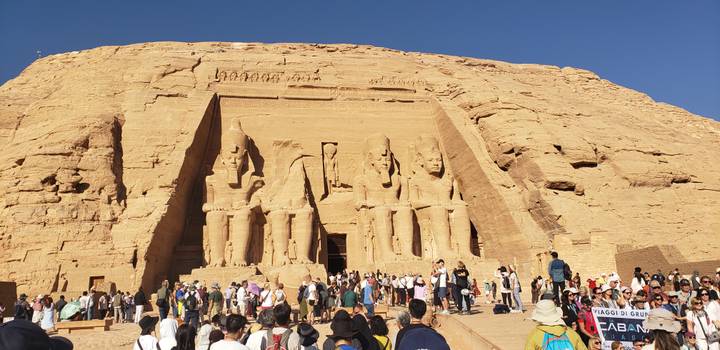 Große Gruppe von Menschen vor den ikonischen Abu Simbel Tempeln, die in eine Felswand gehauen sind.