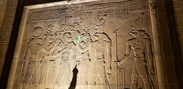 Hieroglyphen-bedeckte Wand mit einem zeigenden Besucher.