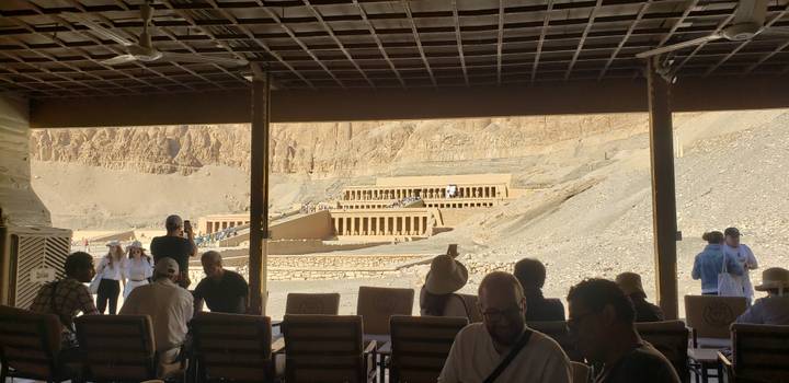 Blick von einem schattigen Bereich auf eine antike Stätte mit Touristen.