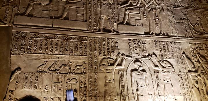 Nahaufnahme von ägyptischen Hieroglyphen, die nachts beleuchtet sind.