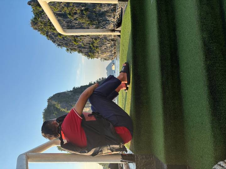 Person seated on a boat with limestone rocks under blue sky.