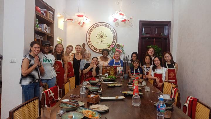 Große Gruppe von Menschen versammelt um einen Tisch bei einem Kochkurs.