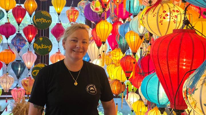 Frau steht inmitten bunter Laternen in einem Geschäft.