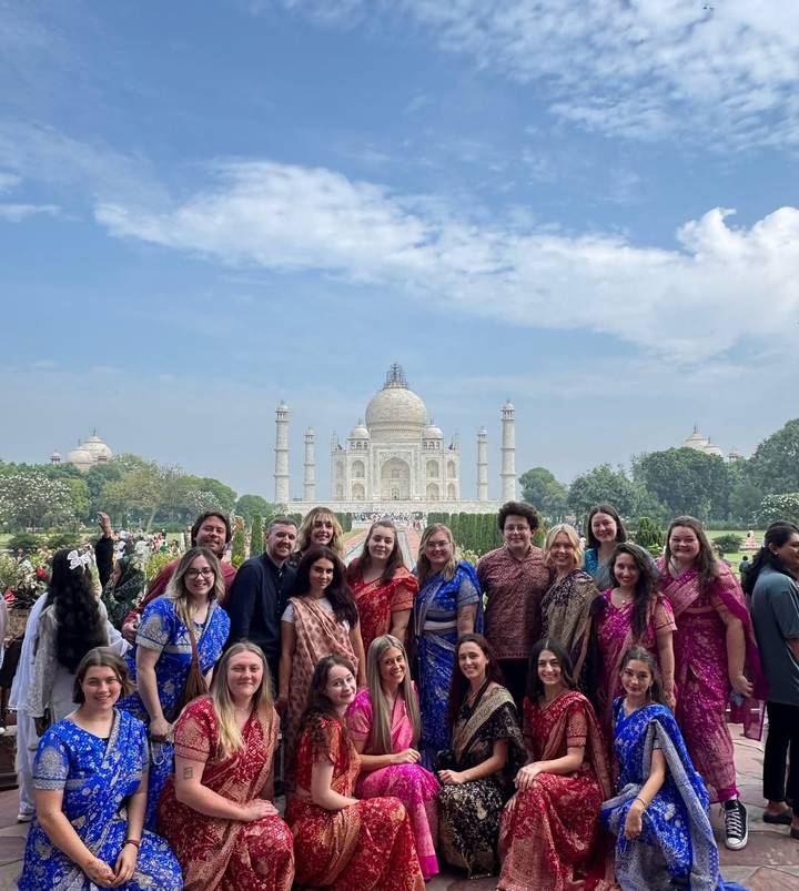 A group of people posing in front of the Taj Mahal.