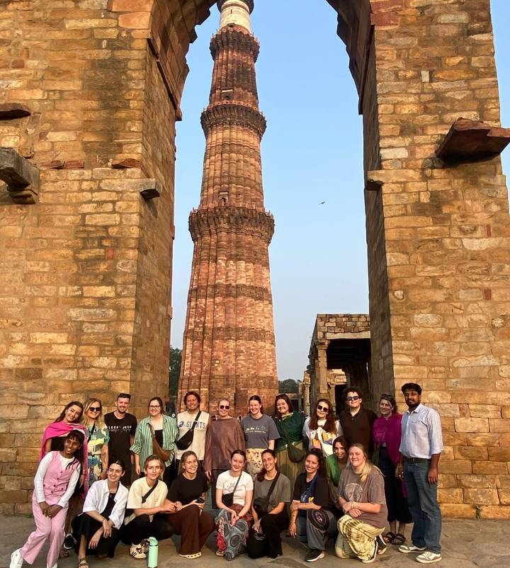 A group of people standing before an ancient stone tower.