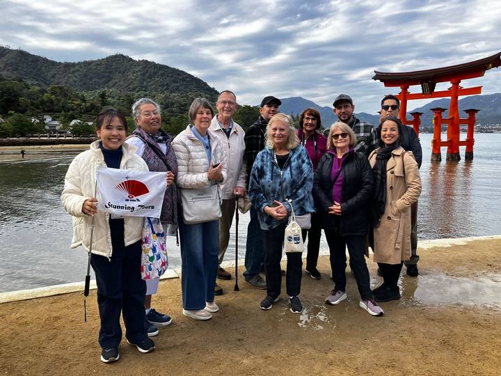 Grupo de turistas posando con el famoso torii de fondo.