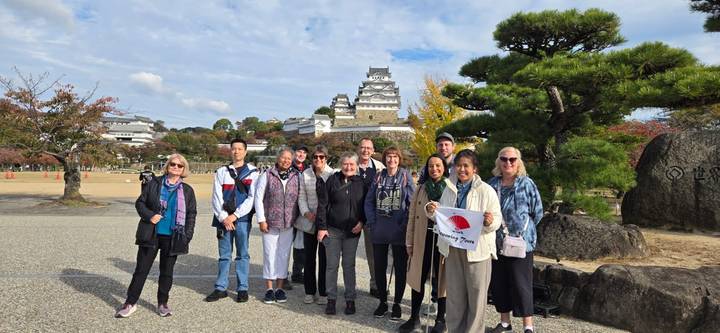 Grupo de personas posando frente a un castillo japonés.
