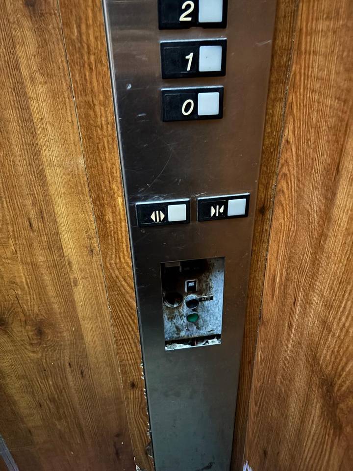 Close-up of elevator buttons and wood panel.