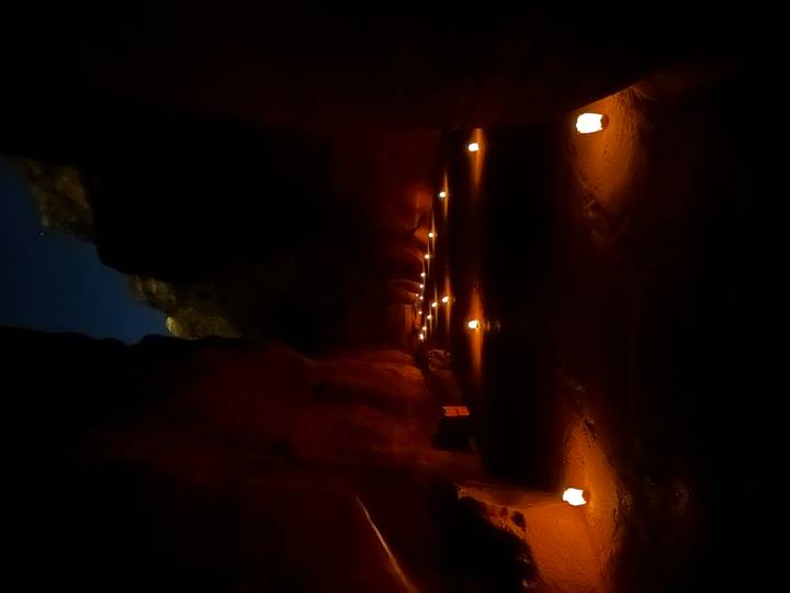 Sentier éclairé par des bougies la nuit, entouré de falaises.