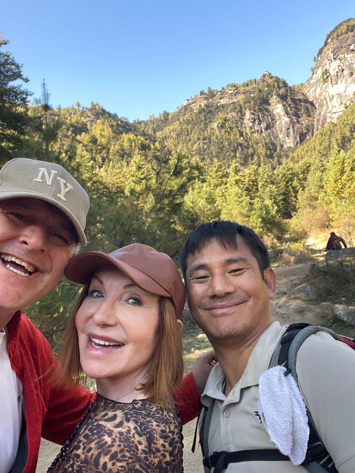 Tres personas sonriendo en una zona boscosa.