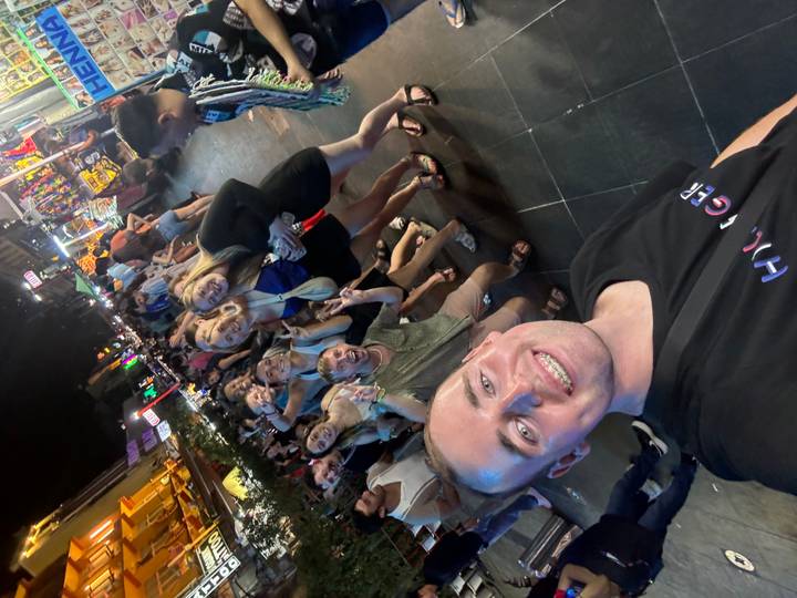 Grupo de personas en una bulliciosa calle de mercado nocturno.