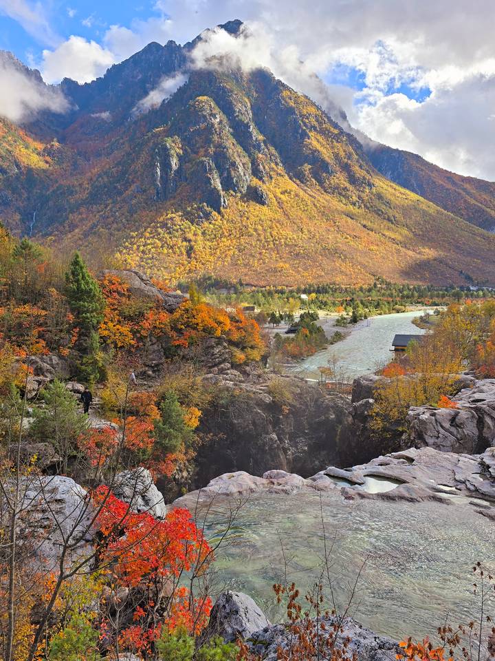 Autumn landscape with flowing river and colorful trees.