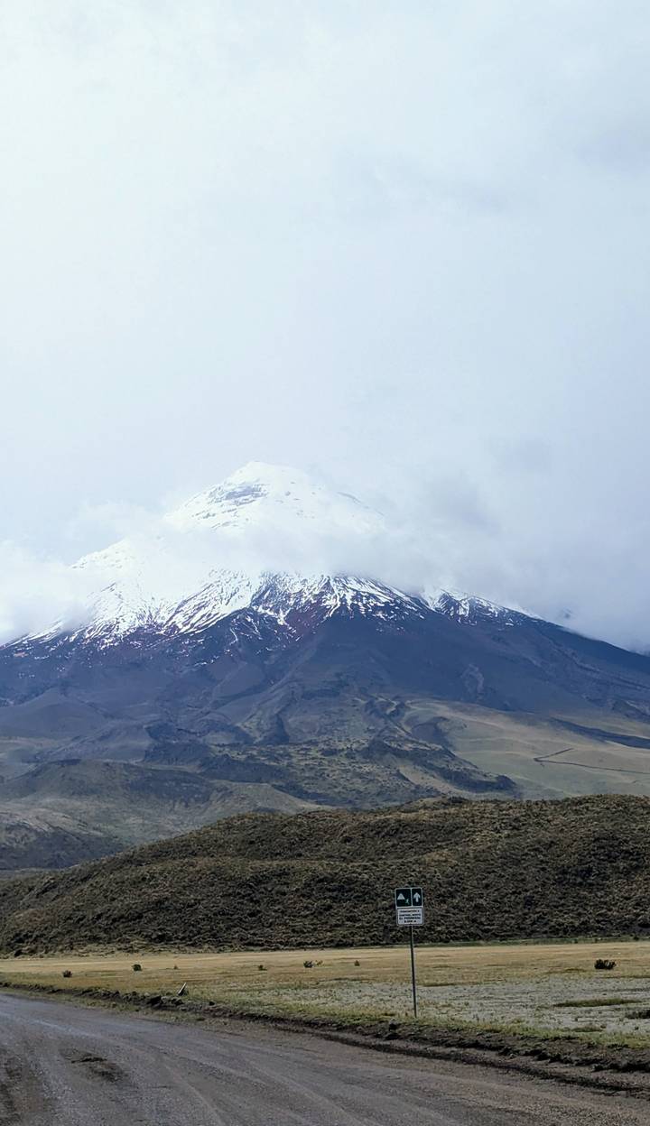 Volcan Cotopaxi enneigé partiellement couvert de nuages.