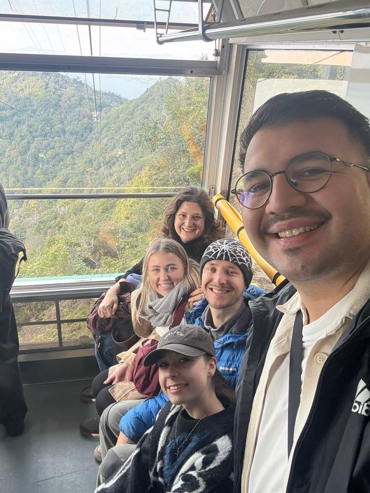 Gruppenselfie in einer Seilbahn mit Waldblick.
