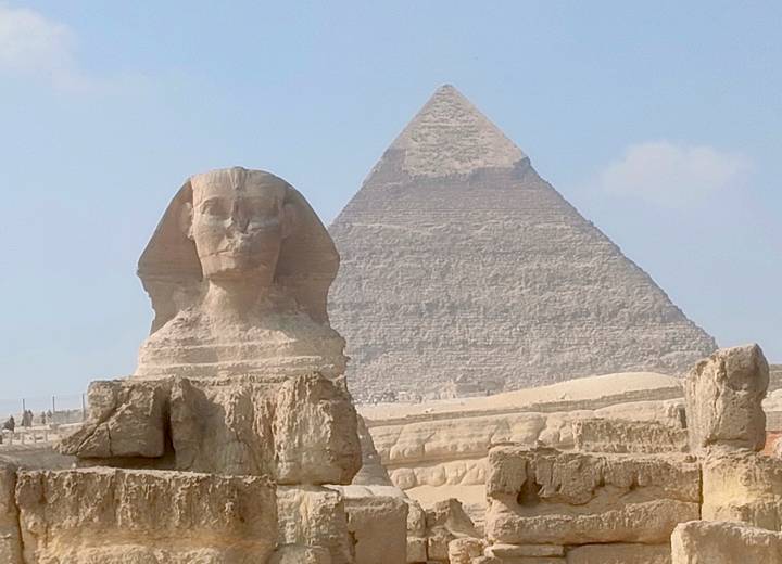 Eine berühmte altägyptische Sphinx und Pyramide unter blauem Himmel.