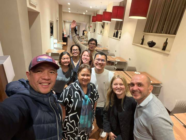 Un groupe de personnes souriantes prenant un selfie à l'intérieur.