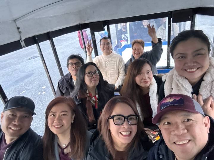 Groupe de personnes souriantes prenant un selfie dans un véhicule.