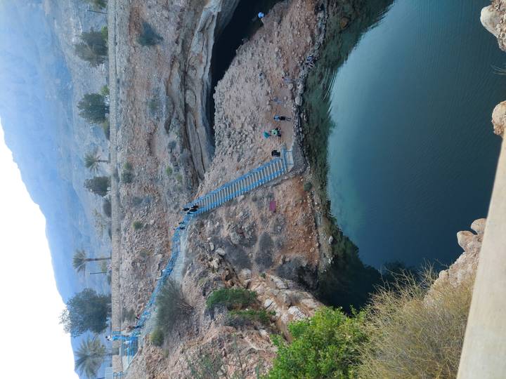 Turistas visitando una piscina natural de agua en una zona rocosa.