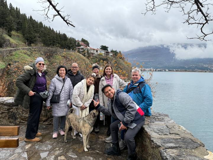 Un grupo de personas posando en un lago pintoresco con colinas de fondo