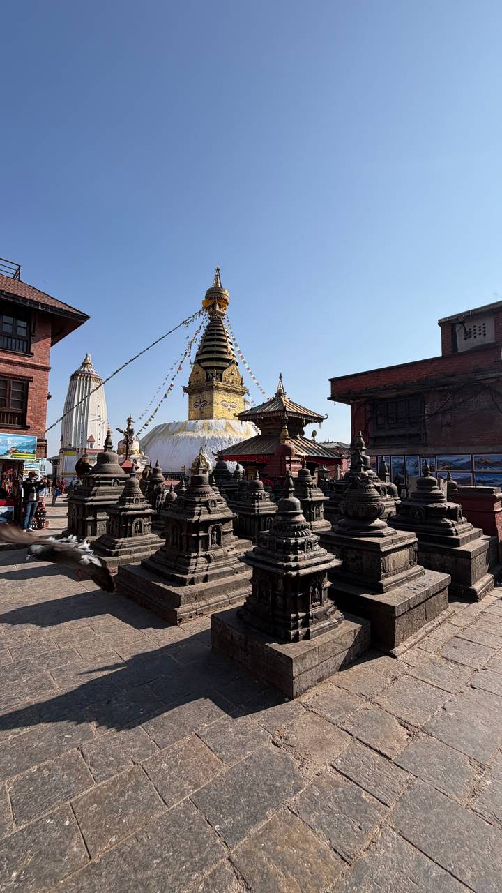 Buddhistische Stupas und Tempelstrukturen mit Gebetsfahnen und blauem Himmel.