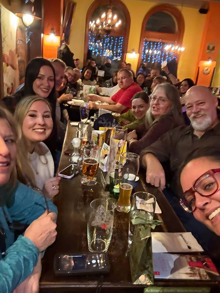 Gruppe von Leuten, die an einer Bar sitzen, Getränke haben und eine entspannte Atmosphäre genießen.