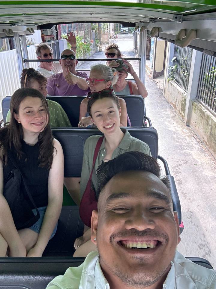 Nahaufnahme von Touristen, die lächeln, während sie in einem offenen Fahrzeug fahren.