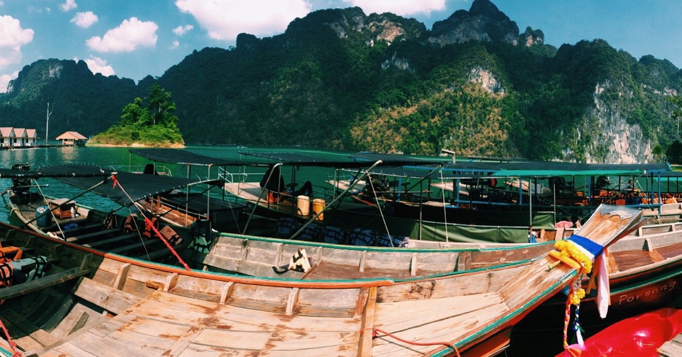 Traditional long-tail boats near limestone cliffs.