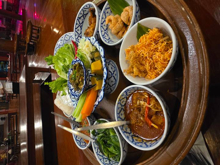 Thailändische Gerichte in traditionellen Schüsseln auf einem Holztablett.