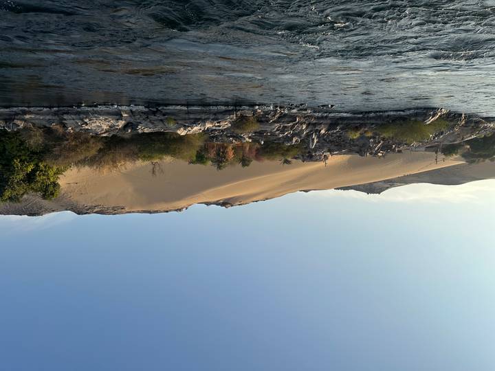 Paisaje de dunas de arena del desierto a lo largo de un río bajo un cielo azul.