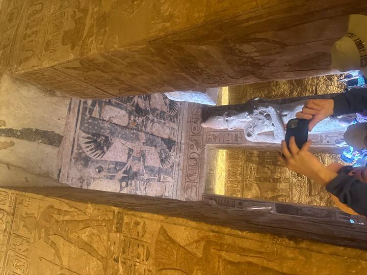 Interior de estructura antigua con jeroglíficos y personas.