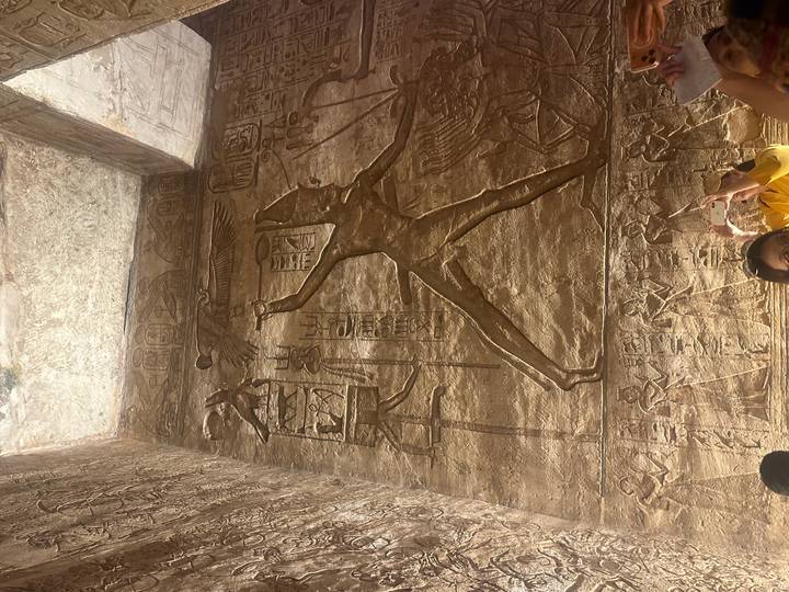 Jeroglíficos en la pared de un templo con grabados iluminados.