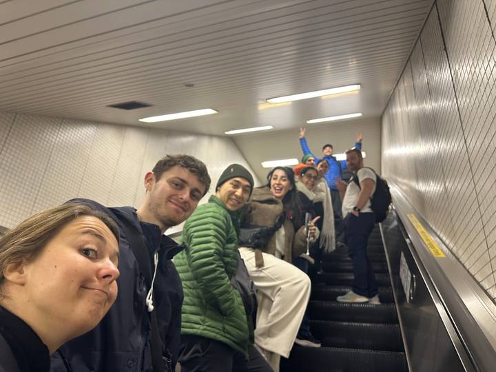 Un groupe de personnes posant sur un escalier mécanique dans un environnement de métro.