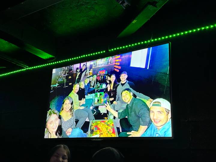 Un groupe de personnes assises à une table dans un bar ou une boîte de nuit avec des lumières colorées.